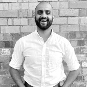Facilitator Ananth Gopal standing in front of a brick wall